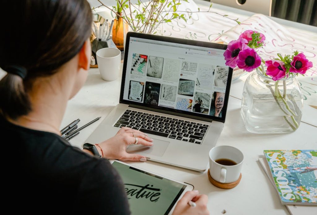 A person sitting at a desk and reading about adaptive vs. responsive design on their laptop
